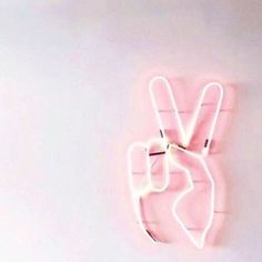 a pink neon sign hanging on the side of a wall with a peace sign in front of it