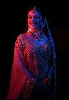 a woman in a sari and jewelry poses for the camera with her hands on her hips