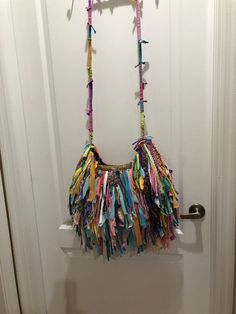 a purse hanging on a door handle with colorful ribbons attached to the front and back