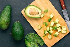 an avocado cut in half on a cutting board with a knife next to it