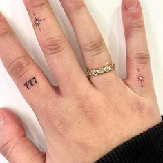 a person's hand with two small tattoos on their fingers and the other finger