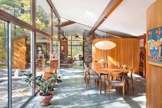 a dining room table and chairs in front of large windows with wood paneling on the walls