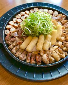 a blue plate topped with meat and veggies on top of a wooden table