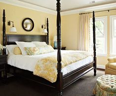 a bedroom with a four post bed, yellow walls and carpeted flooring is shown