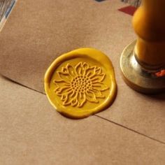 a wax stamp sitting on top of a piece of brown paper next to a candle