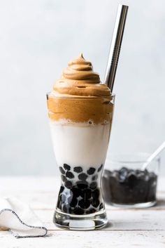 a glass filled with coffee and topped with whipped cream, chocolate pudding and milkshake