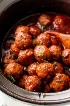 the meatballs are being cooked in the crockpot with sauce and parsley