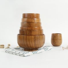 a stack of wooden bowls sitting on top of a white table next to a napkin