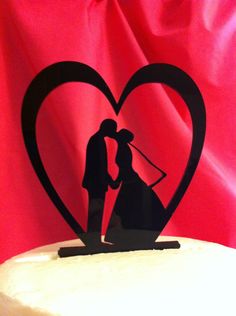 a wedding cake topper with a silhouette of a bride and groom in a heart