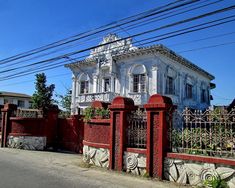 an old white house with red iron fence