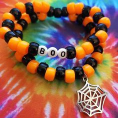 two bracelets with black and orange beads are on top of a tie dye table