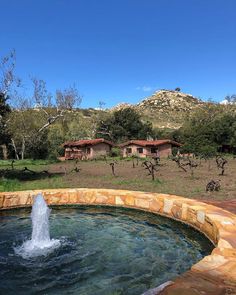 an outdoor hot tub in the middle of a field with mountains in the back ground