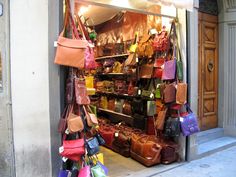 bags and purses are on display in the doorway of a storefront, which is lit up by street lights