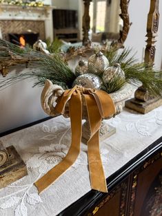 a table topped with a vase filled with greenery next to a fire place mantle