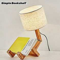 a small wooden table lamp sitting on top of a white table next to a yellow book