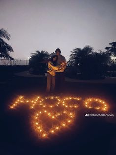 a man and woman standing next to each other in front of the word love spelled out with lights