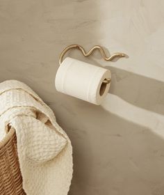 a white towel is hanging on the wall next to a basket and toilet paper roll