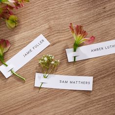 flowers and name tags on a wooden table with names pinned to the labels that say same