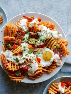 two plates filled with cheesy pasta and fried eggs