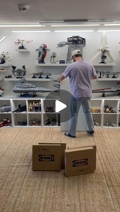 a man standing on top of two boxes in front of shelves filled with legos