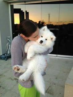 a woman holding a small white dog in her arms