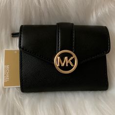 Michael Kors Carmen Medium Flap Bifold Wallet *New With Tags *Black Non-Leather Vegan Material Exterior *Black Non-Leather Vegan Material And Black Nylon Interior *Interior: (8) Card Slots, (1) Bill Slot, (1) Zip Slot *Exterior: (1) Card Slot *Gold-Tone Mk Snap Button Closure, Gold-Tone Hardware *Approximate Dimensions: 4.75" X 3.75" X 1.25" Black Bifold Wallet With Logo, Michael Kors Black Wallet For Everyday Use, Compact Black Trifold Wallet, Black Trifold Wallet For Evening, Michael Kors Leather Evening Wallet, Michael Kors Leather Wallets For Evening, Michael Kors Wallet, Bifold Wallet, Black Nylon