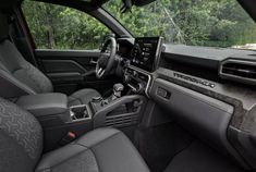 the interior of a vehicle with grey leather seats and dashboards, trees in the background