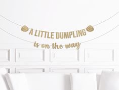 a little dumpling is on the way banner hanging from a string in a living room