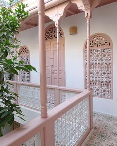 an ornate balcony with pink ironwork and white walls