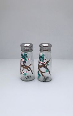 two glass salt and pepper shakers with birds on the branch painted on each one