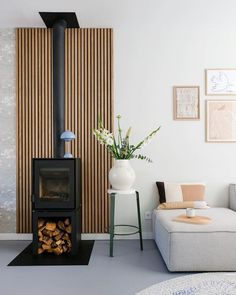 a living room filled with furniture and a fire place in front of a wall mounted wood heater