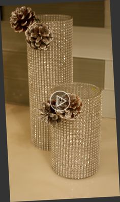 two glass vases with pine cones on the top and one is made out of beads