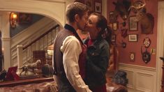 a man and woman kissing in a living room with antlers on the wall behind them