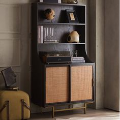 a bookcase with an old record player on top and a suitcase next to it