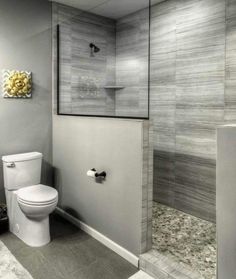 a white toilet sitting in a bathroom next to a walk in shower and tiled walls