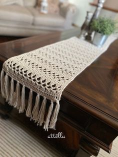 a crocheted table runner with tassels sits on top of a coffee table