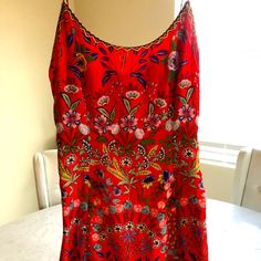 a red top with floral designs on it sitting on a table next to a window