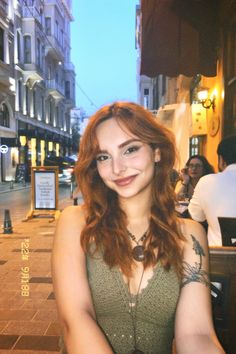 a woman with red hair is smiling at the camera