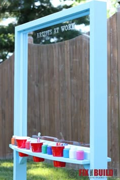 an outdoor art work area with paint buckets on it and a mirror in the background