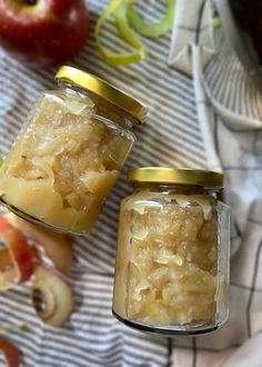 two jars filled with food sitting on top of a table next to an apple slice