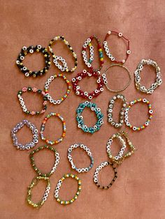 many different bracelets are arranged on a pink surface, with beads in the shape of letters