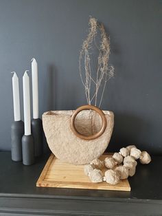 a wooden bowl sitting on top of a table next to some white candles and flowers