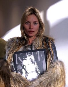 a woman in fur coat holding up a magazine