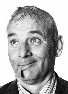 a black and white photo of a man making a funny face with his tongue sticking out