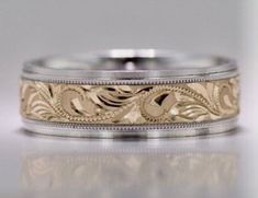 two tone gold wedding rings with intricate engraving on the sides and an engraved design in the middle