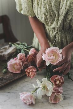 a woman is arranging flowers on a table