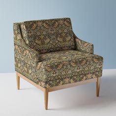 an upholstered chair sitting on top of a white floor next to a blue wall