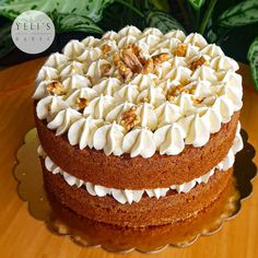 a cake with white frosting and walnuts on top is sitting on a plate