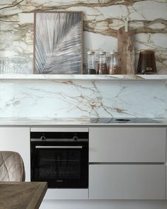 a kitchen with marble counter tops and white cupboards next to a stove top oven