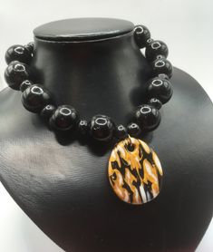 I've used the Japanese mokume gane technique to create this polymer clay pendant. It comprises gold, black and white polymer clay. The pendant has been teamed with chunky black glass beads and smaller wooden beads.  I chose white beads so that the marbled pendant would really stand out. (And I'm a big fan of the chunky!) The necklace is closed with a lobster claw lock and extends to 49cm maximum with use of the extender chain. Use the lobster claw to meet the length that best suits you. The pend Unique Black Oval Pendant Necklace, Unique Black Necklace With Large Pendant, Unique Black Necklace For Gift, Unique Black Necklaces For Gifts, Handmade Polymer Clay Round Pendant Necklace, Black Polymer Clay Jewelry Gift, Handmade Round Polymer Clay Pendant Necklace, Adjustable Black Medallion Jewelry, Adjustable Black Medallion Necklace